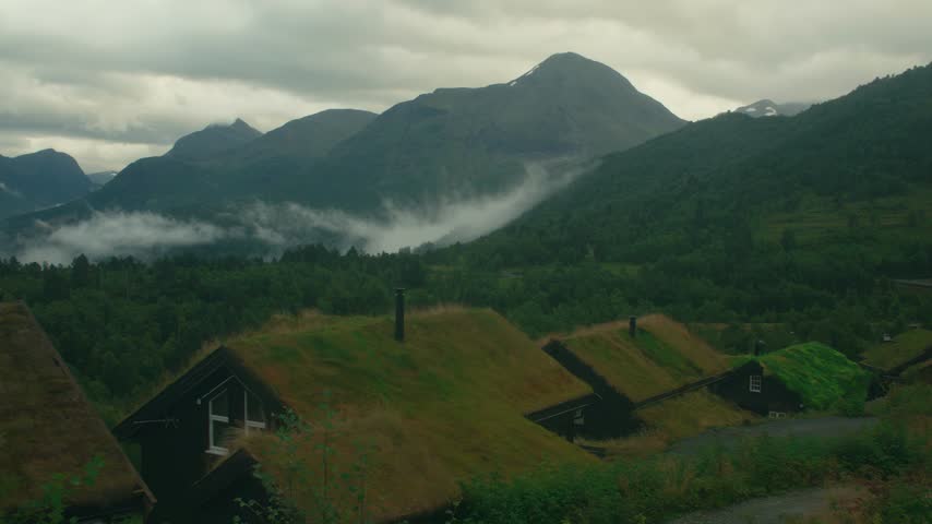 Mountain Valley Scene with Grass Roofed Houses and Fog