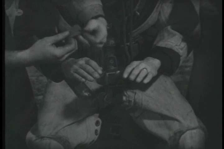 1930s - two men dress another man in deep sea diving gear before a dive during the 1930s