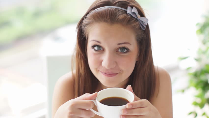 Cute girl enjoying coffee and smiling at camera
