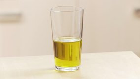 A glass of olive oil being taken off the work surface