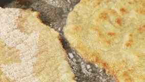 Breaded escalopes being fried in a pan