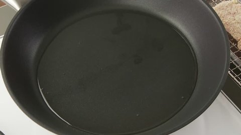 A breaded escalope being fried in a pan