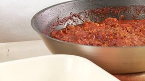 Minced meat sauce being poured into a baking dish