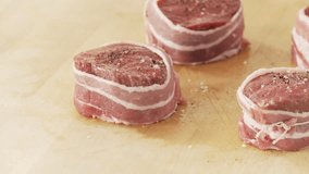 Beef fillet slices wrapped in bacon being secured with kitchen twine