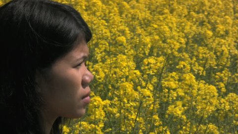 Filipino woman with a flowering canola field in the background