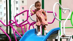 Cheerful child sliding down the chute on the playground