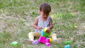 Adorable child playing with construction blocks outdoors