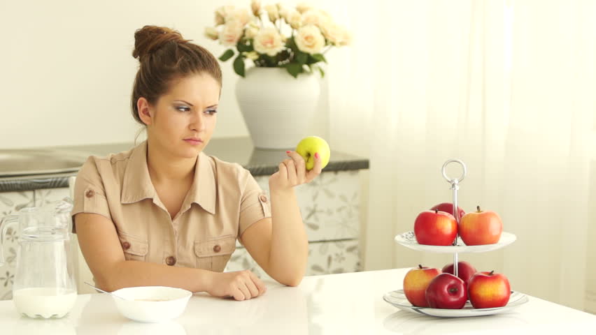 Serious girl with an apple in the kitchen
