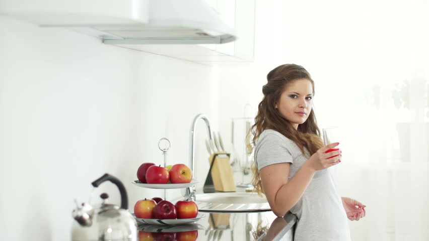 Woman standing in kitchen and drinking juice
