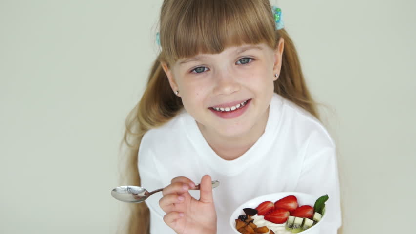Cute girl holds plate with yogurt
