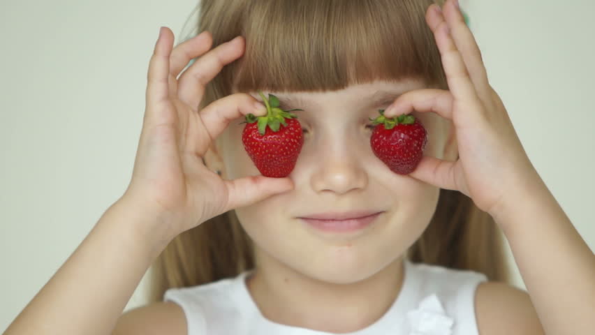 Girl hiding her eyes with two strawberries
