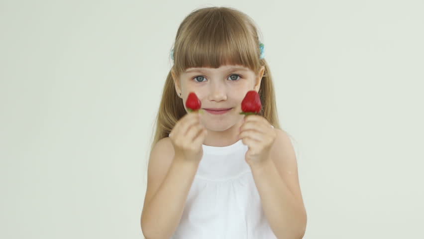 Girl holding two strawberries and smiling at the camera
