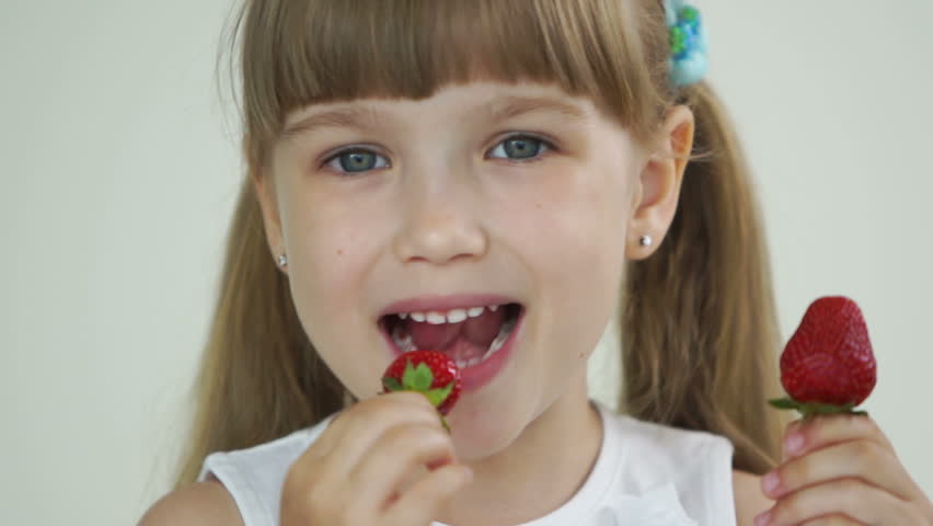 Cute girl eating strawberry and laughing
