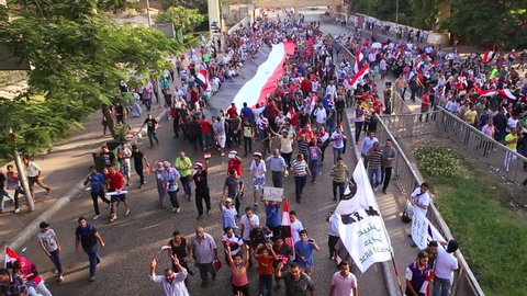 CAIRO, EGYPT - 2013: Protestors march and carry a large flag in Cairo, Egypt.