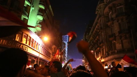 CAIRO, EGYPT - 2013: Protestors wave flags and fireworks go off at a nighttime rally in Cairo, Egypt.