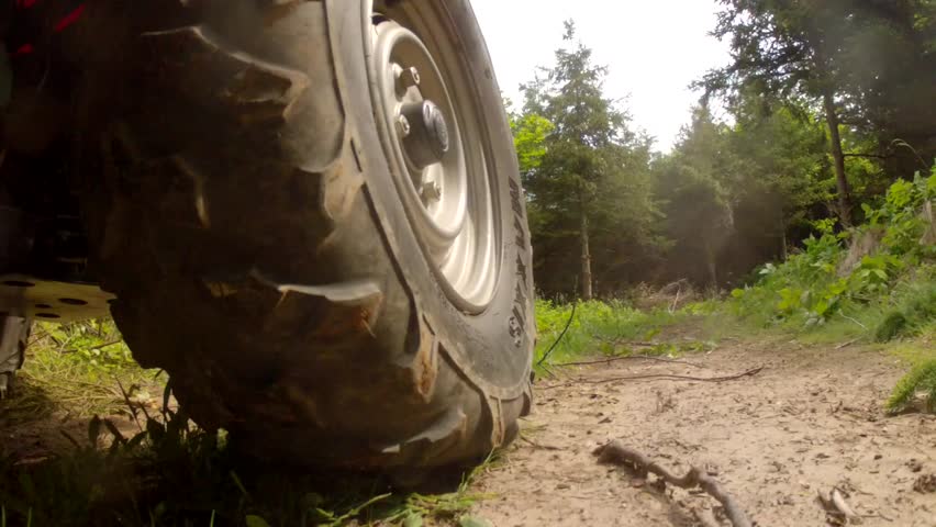 A low shot of a four wheeler riding on a dirt road on a mountain