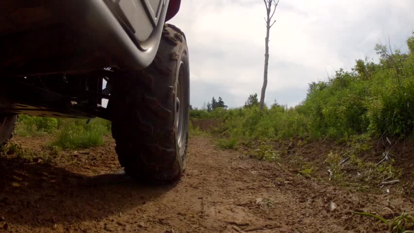 A low shot of a four wheeler riding on a dirt road on a mountain