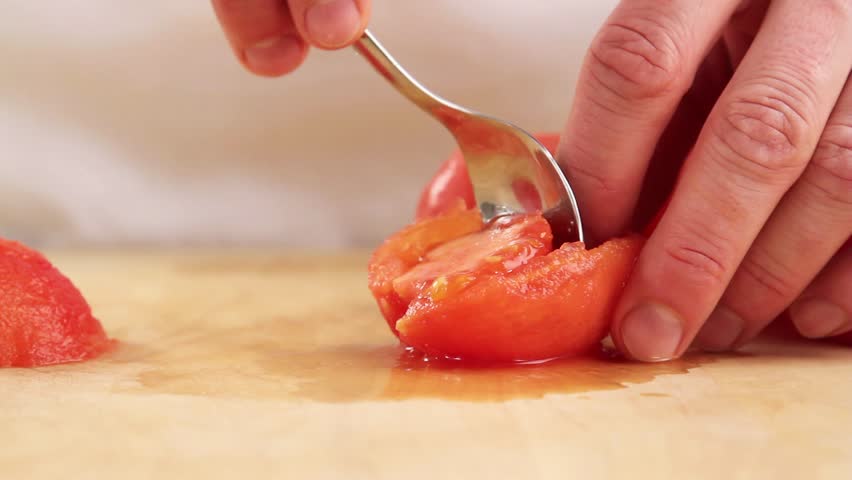 A peeled tomato being deseeded
