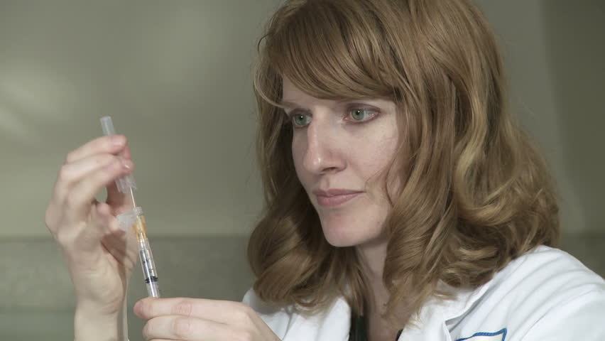 Close up of female doctor getting air bubbles out of a syringe before giving an