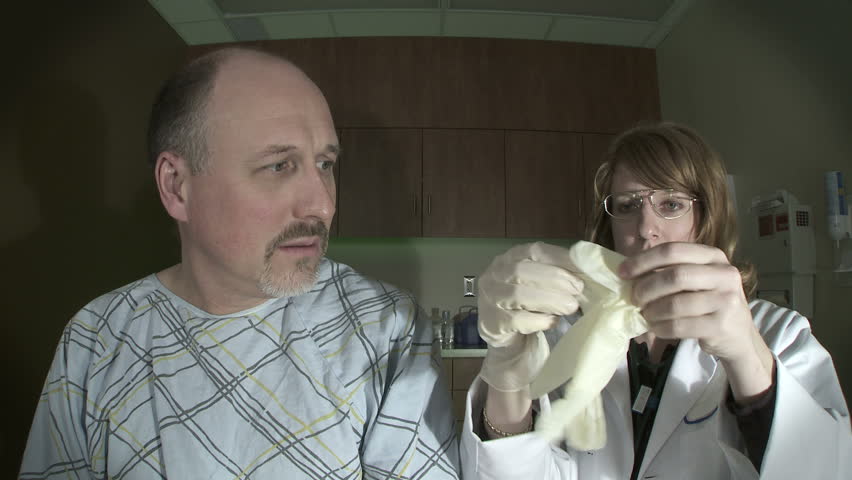 Female doctor in a sinister clinic pulling on rubber gloves while patient looks