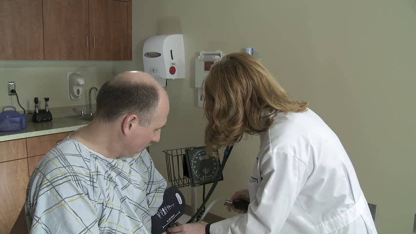 Medium shot of female doctor taking the blood pressure of a mature male patient.