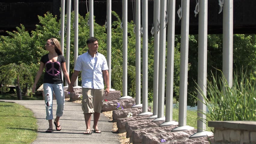 A young couple walk in the park on a sunny day.