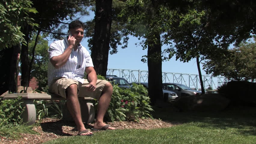 A man talks on a cellular phone in the park.