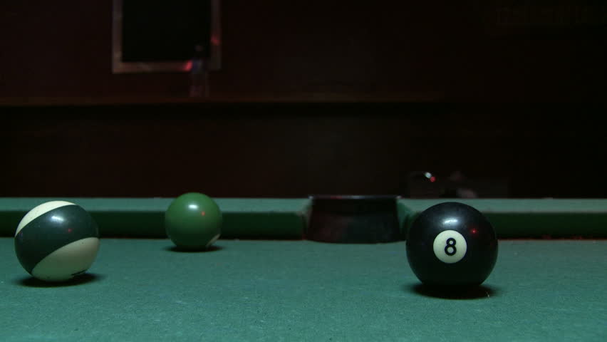 Cue ball hits the 8 ball for a finishing point on a pool table.