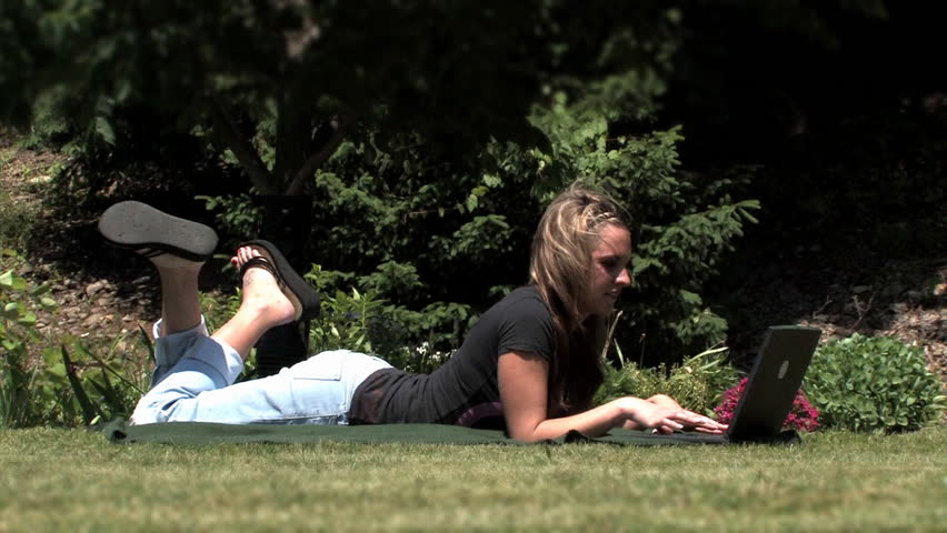 A young woman uses her wireless laptop in the park.