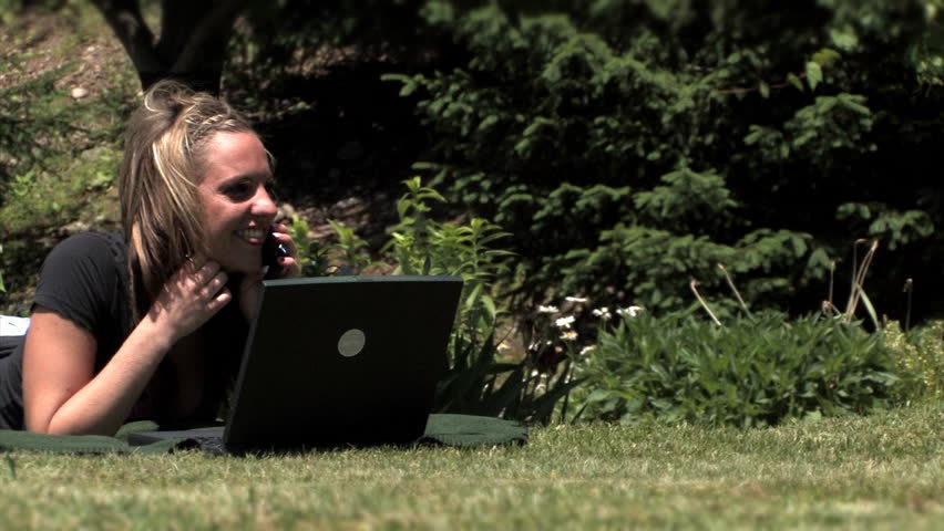 A young woman uses her wireless laptop in the park.