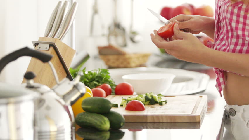 Young woman chopping vegetables in kitchen
