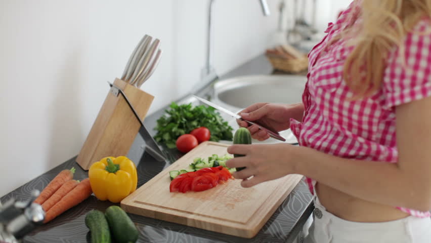 Young woman in kitchen chopping vegetables

