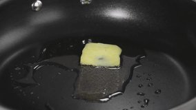 A piece of butter being melted in a pan