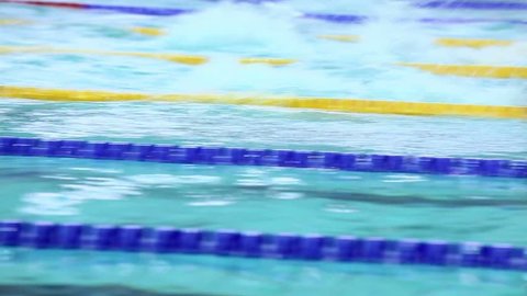 Several sportsmen swim in butterfly style by track at basin