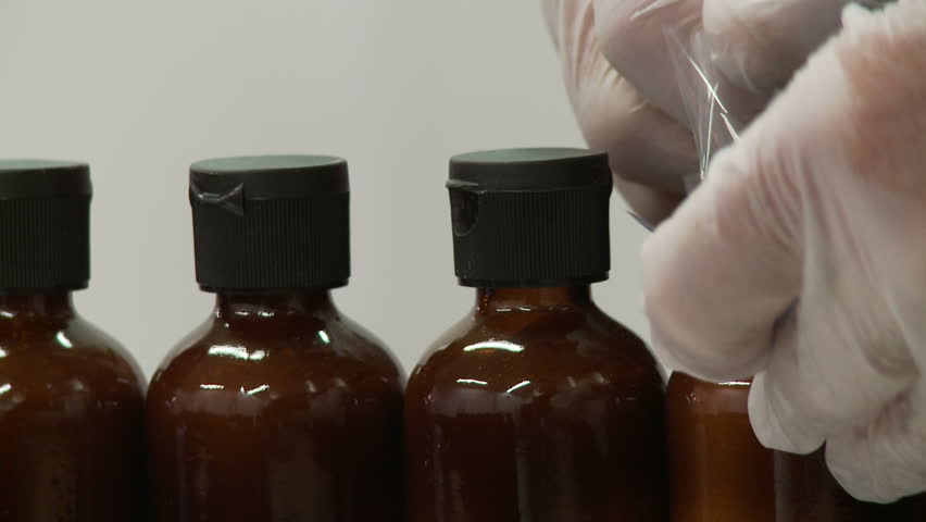 Heat shrink is applied to small glass bottles in a manufacturing process. Two