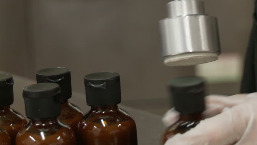 Bottle tops being tightened on to small sauce bottles.