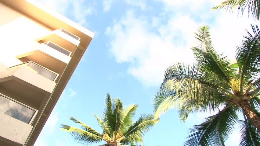 Time lapse at tropical resort with palm trees and patios in Hawaii.