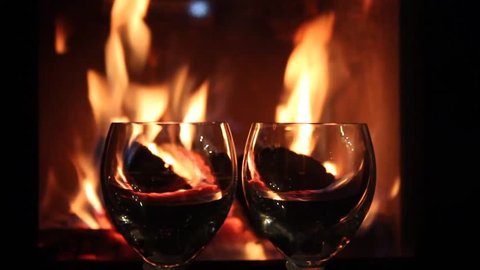 Mulled wine glasses on table in front of burning fireplace. Stock