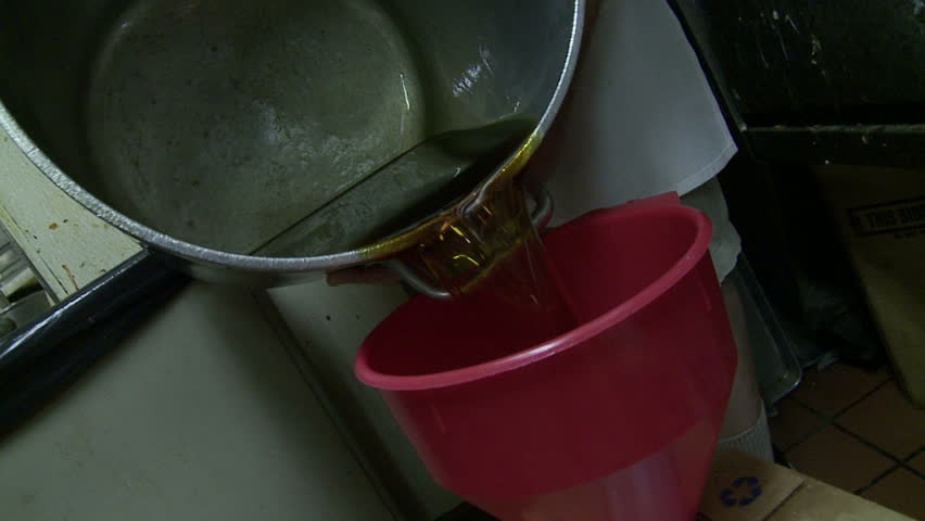 Pouring used corn oil from a restaurant frier back into a container for
