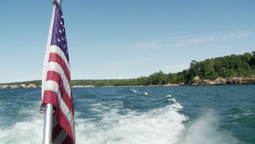 Star and Stripes waving from the back of a boat touring the Pictured Rocks