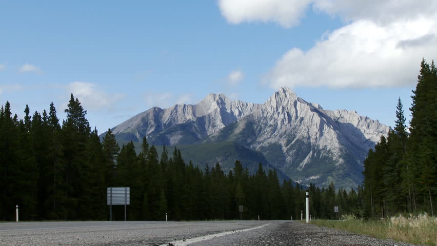 View of the Rocky Mountains near Barrier Lake, Alberta, Canada.  Car drives past