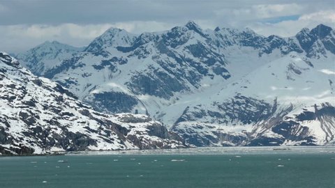 Glacier Bay iceberg floating snow covered mountains Alaska.  Near Margerie Glacier a 21 mile long and mile wide tide water glacier. Cruise ships gets incredible view. Most active glacier for Calving.