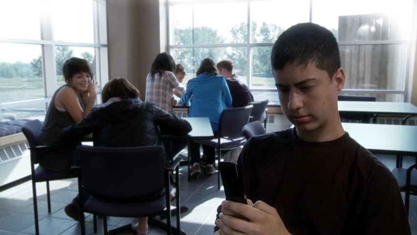 High school student sits in canteen, sending text messages, oblivious to the