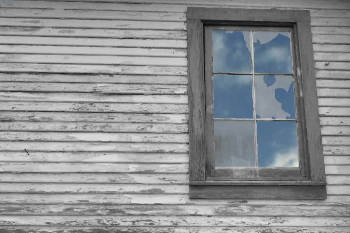 Composite with rustic house window and time lapse of fast moving clouds.