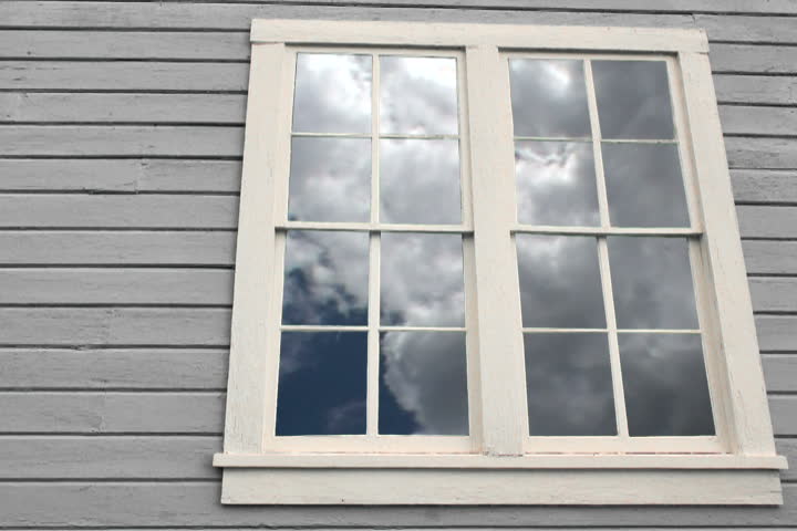 Composite with house window and time lapse of fast moving clouds.
