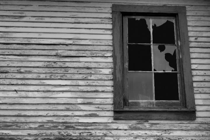 Composite with rustic house window and time lapse of full moon and fast moving clouds.