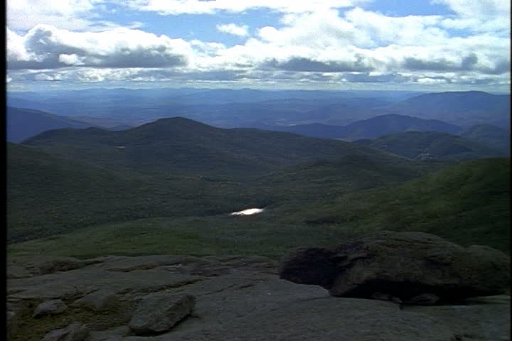 Wide shot of the Adirondack mountain range, zoom in to green valley and Lake Tear of the Clouds in Keene, New York.