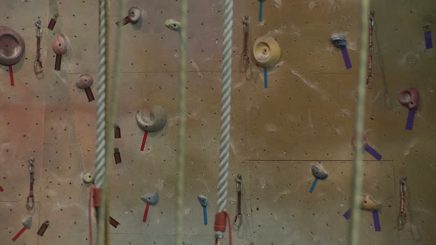 Slow dolly shot, left to right past ropes in an indoor climbing gym with