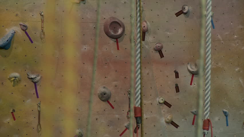 Slow dolly shot, right to left, past ropes in an indoor climbing gym with