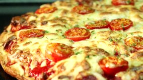 A pizza topped with mozzarella and cherry tomatoes, baking in the oven (close-up)